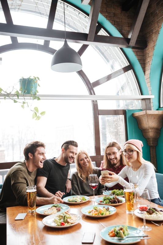 friends-sitting-cafe-using-mobile-phone